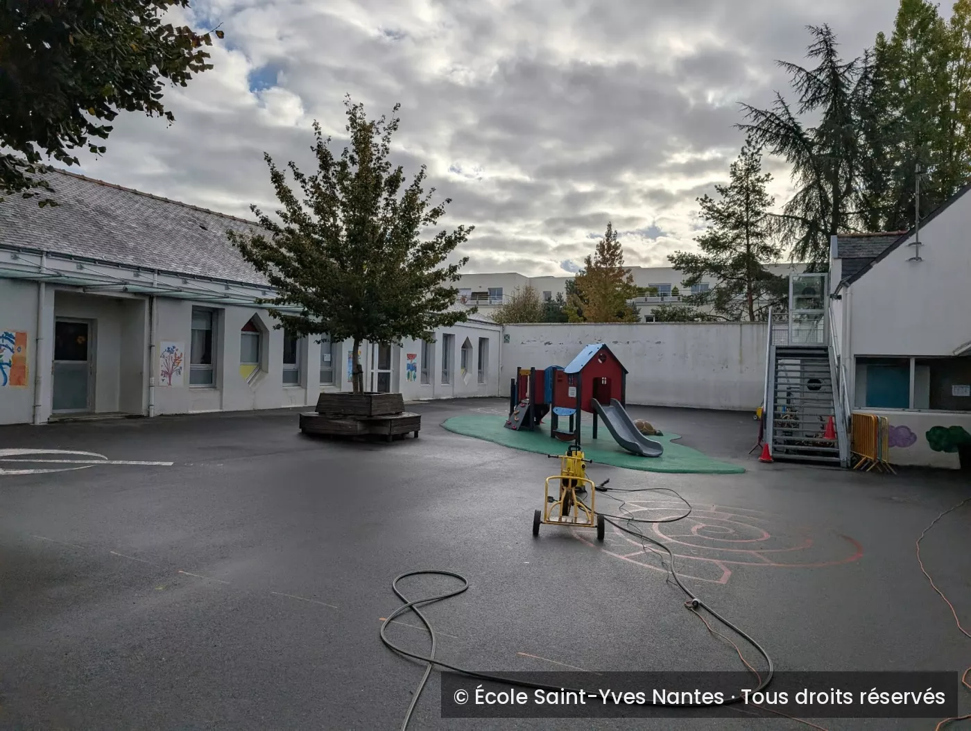La cour nettoyée, avec l'arbre central et la structure de jeux